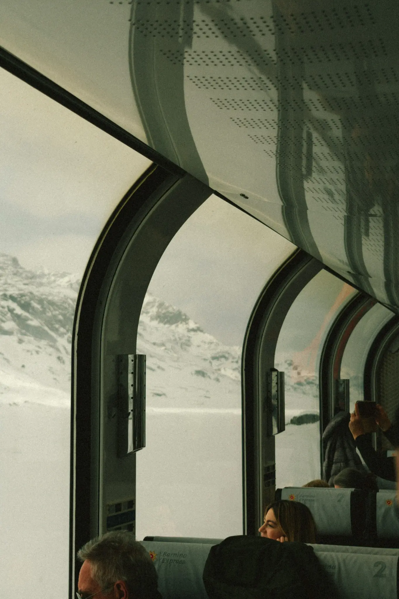 Interior panorámico del Bernina Express con montañas nevadas al otro lado de las ventanas