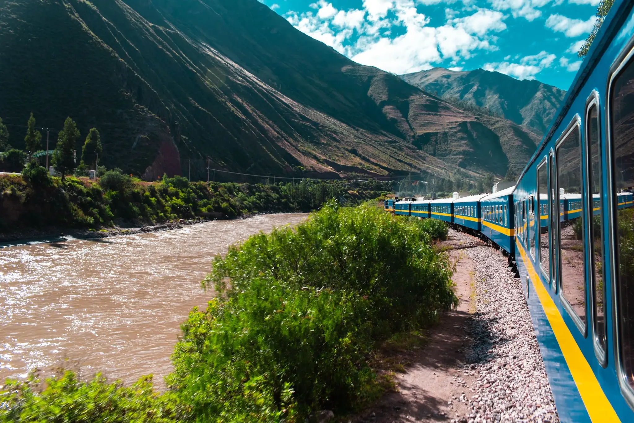 Tren azul recorriendo el Valle Sagrado junto al río